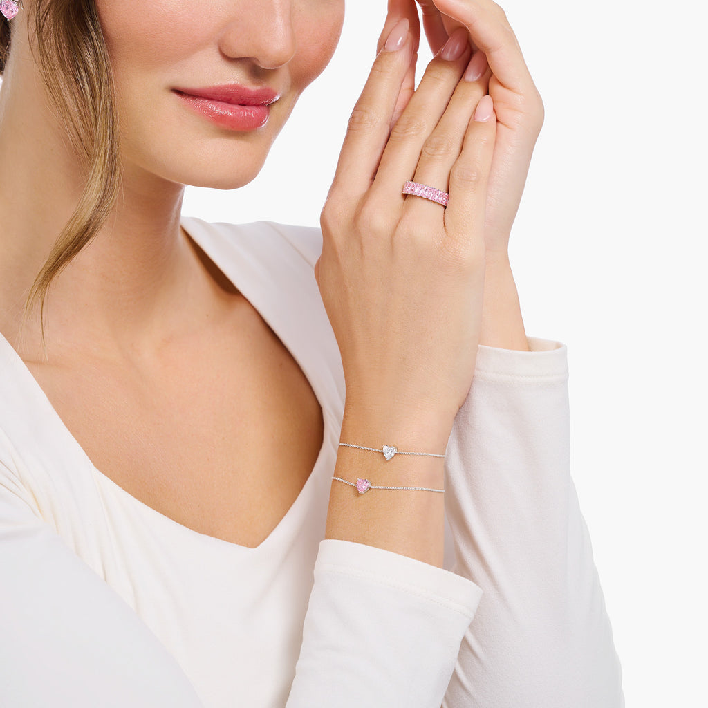 Lady wearing two bracelets and a pink stone ring.